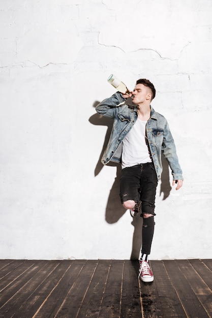 Man standing on floor drinking alcohol posing