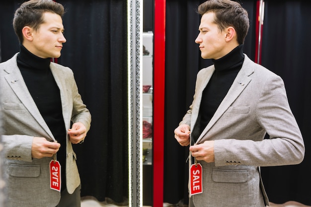 Man standing in front of mirror trying jacket in the shop