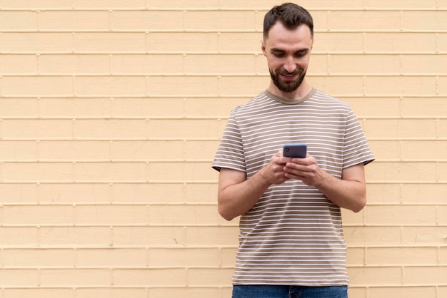 Man standing in front of wall and using his phone