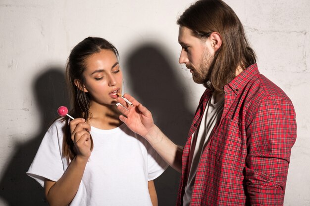 Man standing gives cigarette to girlfriend