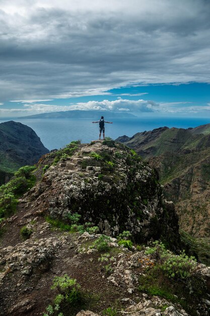 美しい山の風景を背景に丘の上に立っている男