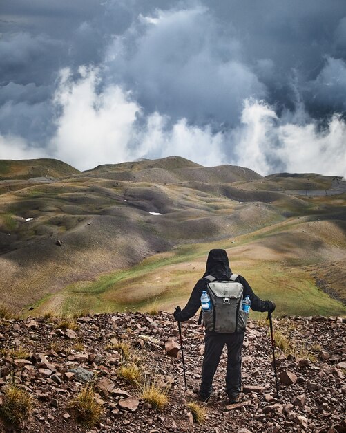 Man standing on a hill while enjoying the view with a cloudy sky