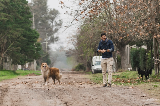 Free photo man standing and his dog standing on dirt track