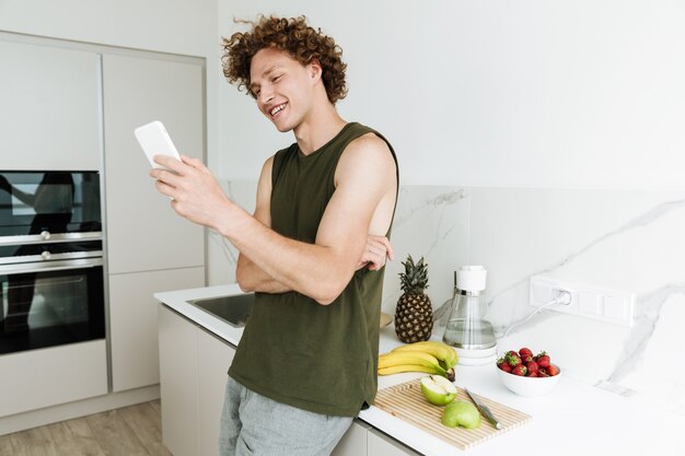 Мужчина стоит на кухне и болтает по телефону