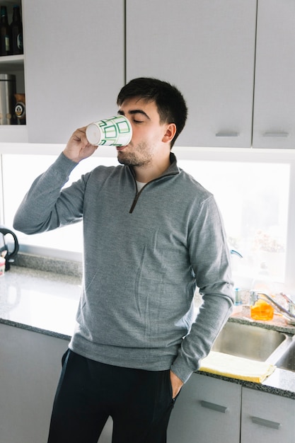 Free photo man standing in kitchen drinking tea