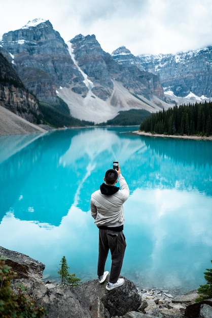 Free photo man standing on moraine lake during daytime