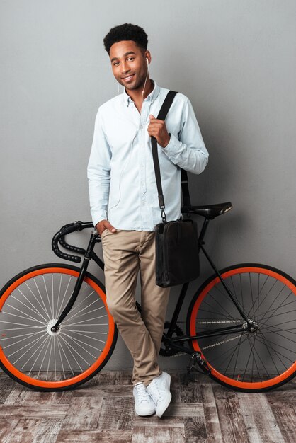Человек, стоящий рядом с велосипедом, изолированных на сером фоне