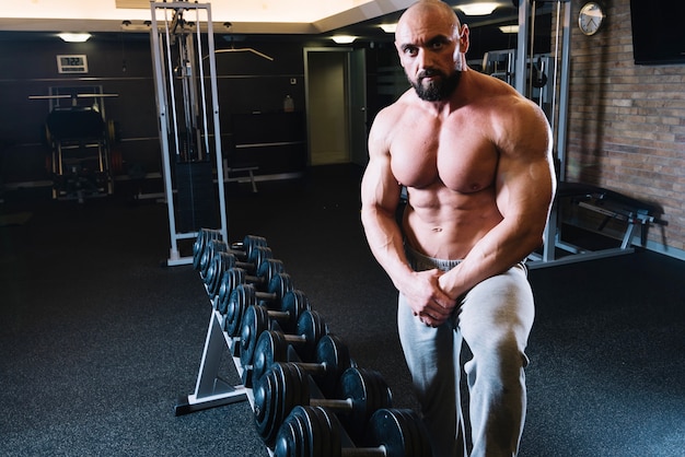 Free photo man standing near dumbbell rack