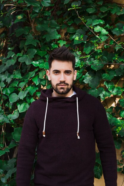 Man standing near green leaves