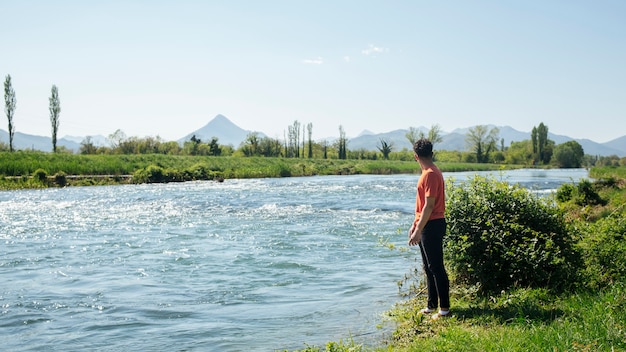 Free photo man standing near natural flowing river