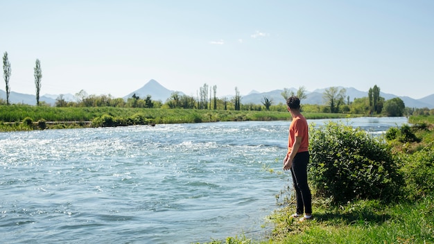 Man standing near natural flowing river