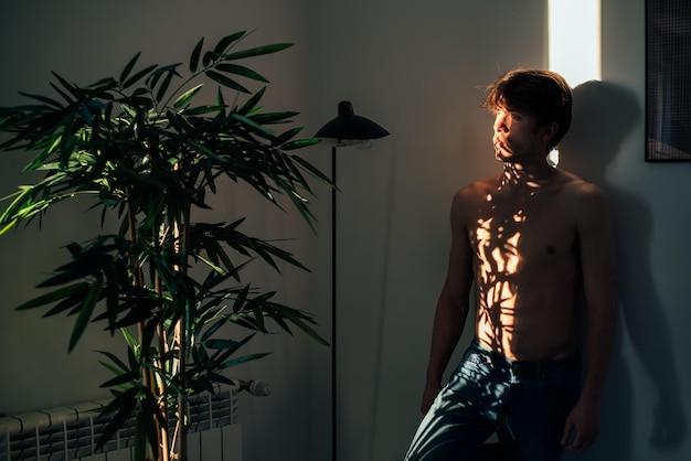 Free photo man standing near plant with shadow light