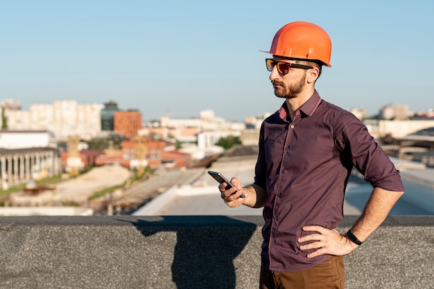 Бесплатное фото Человек, стоящий на вершине здания с телефоном в руке