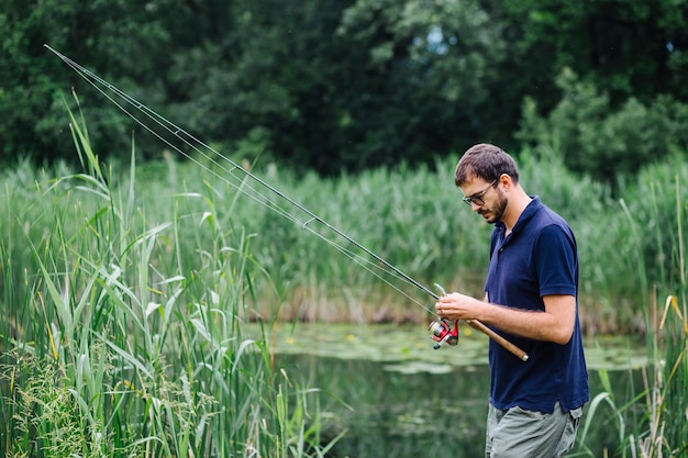 Man standing in the pool tying fishing hook