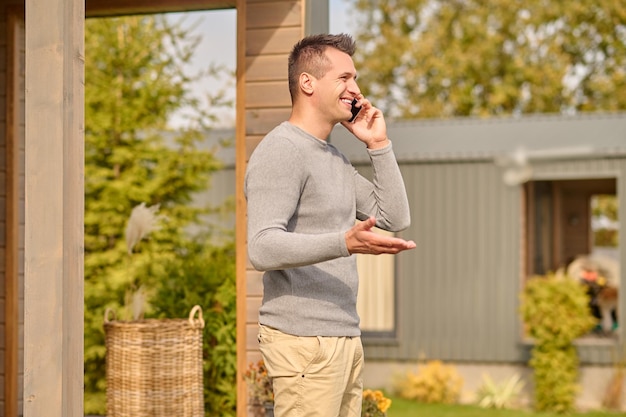 屋外でスマートフォンで話しているカメラに横に立っている男