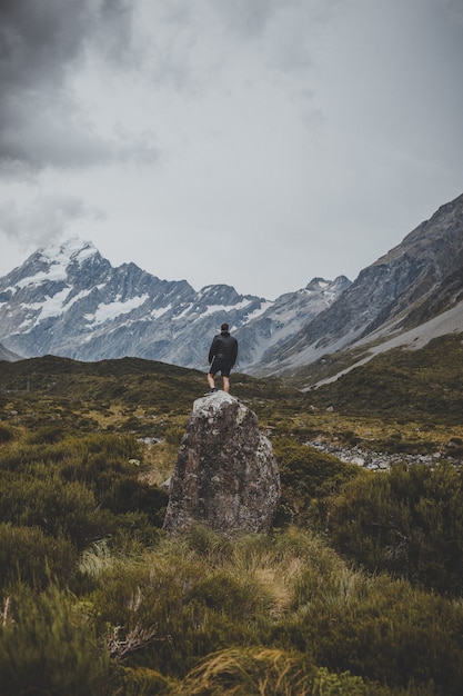 ニュージーランドのマウントクックの景色を望むフッカーバレートラックの石の上に立っている人