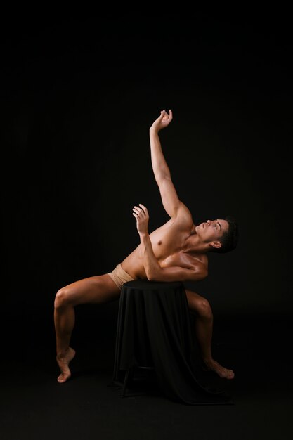 Man standing on toes crouching leaning on chair