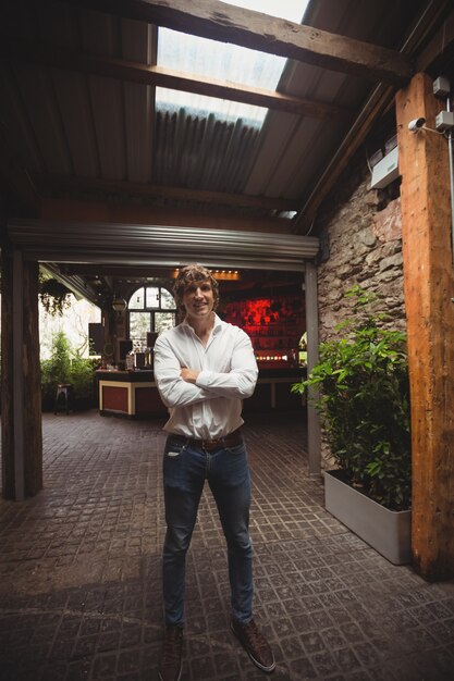 Man standing with arms crossed in bar