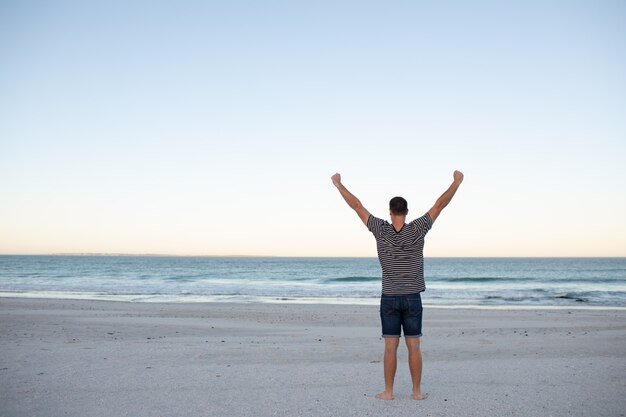 Man standing with arms outstretched on the beach 