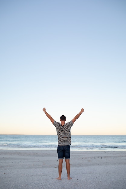 Man standing with arms up on the beach 