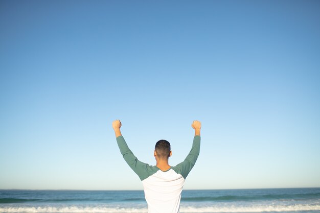 Man standing with arms up on the beach