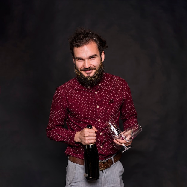 Uomo in piedi con bottiglia di champagne e bicchieri