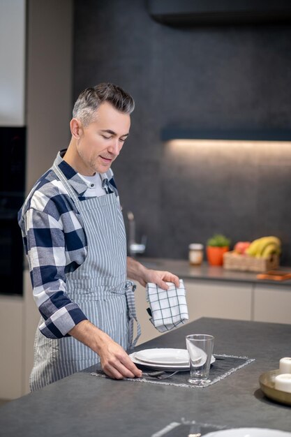 Man standing with napkin near table touching fork