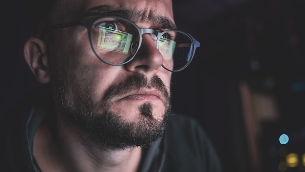 Free photo a man stares intently at a computer screen in the dark at night