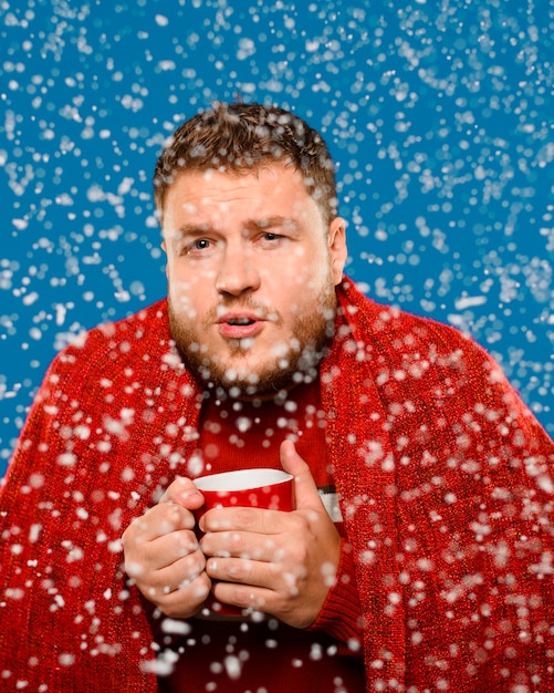 Free photo man staying in snow while holding a cup