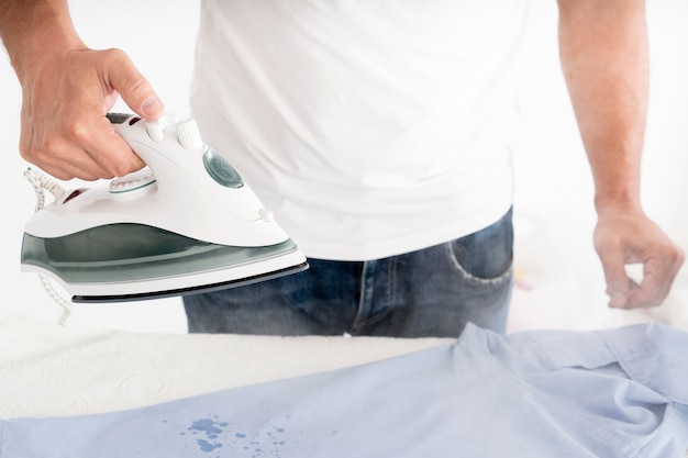 Free photo man steaming clothes with clothing iron