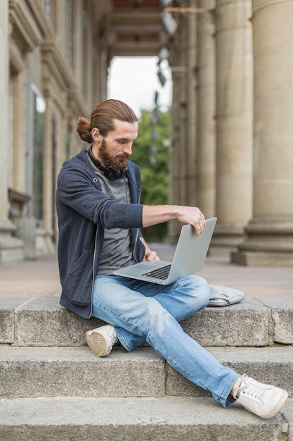 Man on steps in the city working on laptop