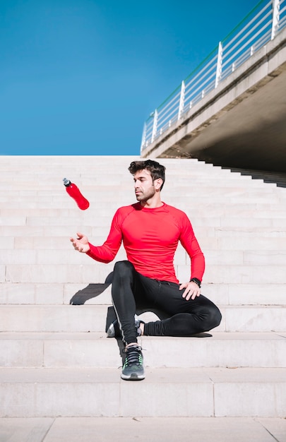 Man on steps throwing bottle up