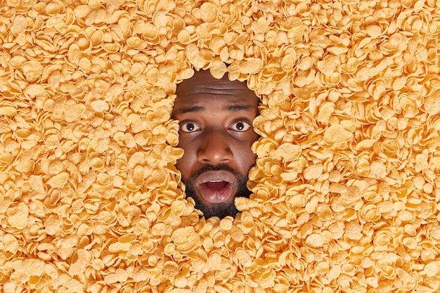 Foto gratuita l'uomo infila la testa nei cornflakes mangia i cereali per colazione reagisce sorprendentemente a qualcosa di incredibile mantiene una dieta sana