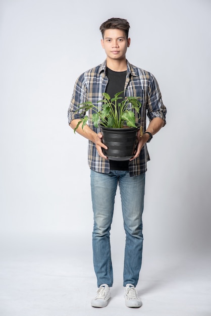 Foto gratuita un uomo stava in piedi e teneva in mano un vaso per piante.