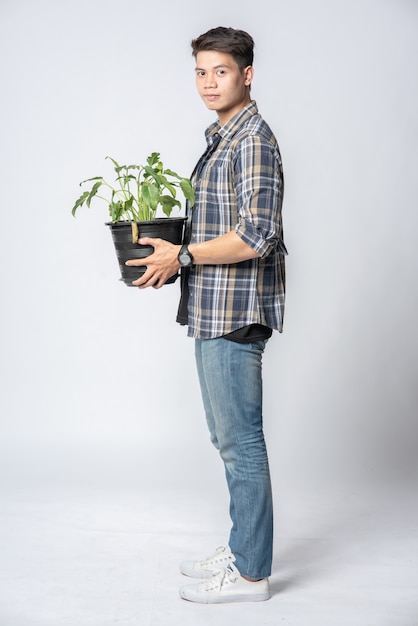 Free photo a man stood and held a plant pot in his house.