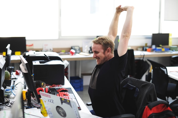 Man stretching arms during break time at office