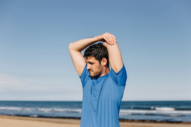 Free photo man stretching at the beach