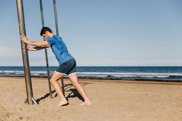 Man stretching on pole at the beach