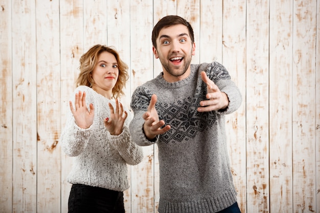 Man stretching  smiling girl refuse over wooden wall