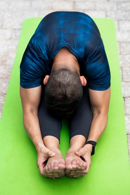 Foto gratuita uomo che si estende mentre si fa yoga all'esterno