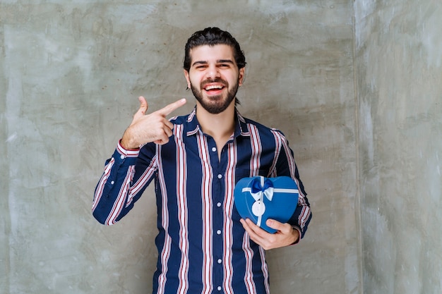 Man in striped shirt holding a blue heart shape gift box