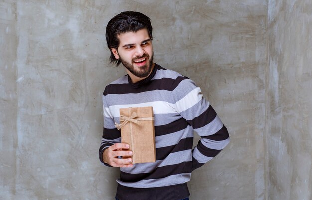 Man in striped shirt holding a cardboard gift box and smiling