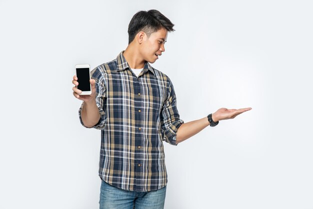 A man in a striped shirt opens his left hand and holds a smartphone