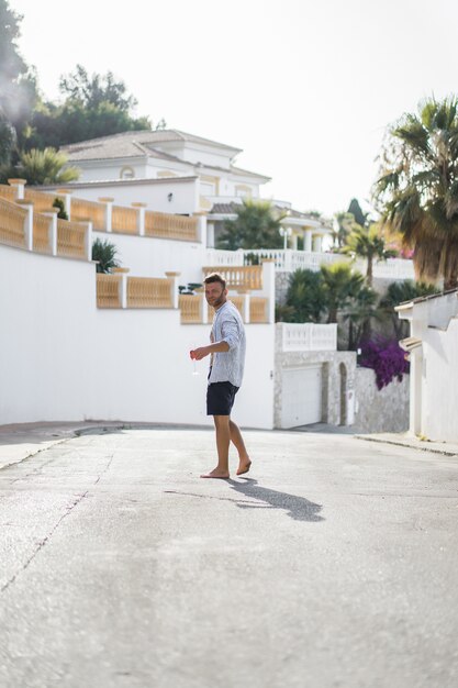 줄무늬 셔츠를 입은 남자가 작은 스페인 마을의 거리를 걷습니다.