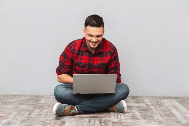 Man student working on laptop while sitting on the floor