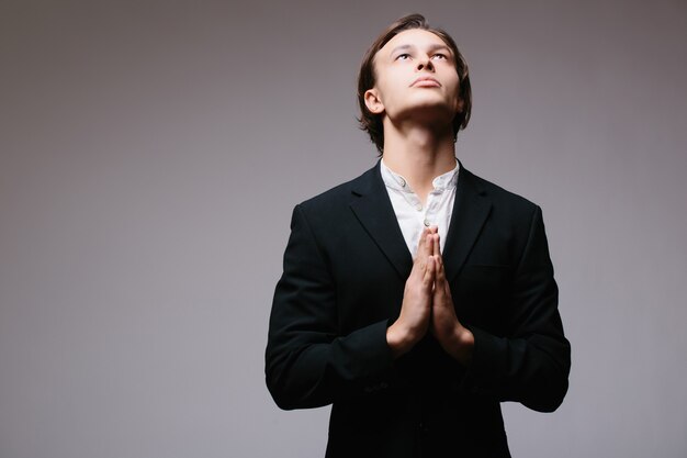 Man in suit in devout prayer position isolated on gray