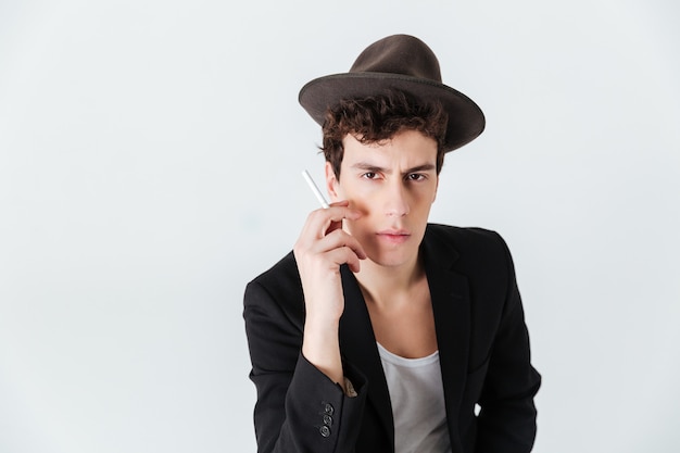 Man in suit and hat holding cigarette