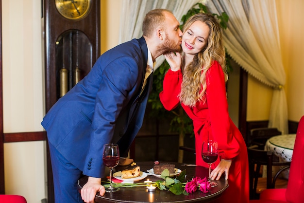 Man in suit kissing woman on cheek above table 