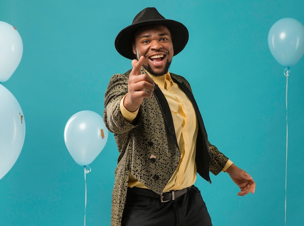 Free photo man in suit and sunglasses at party with balloons pointing