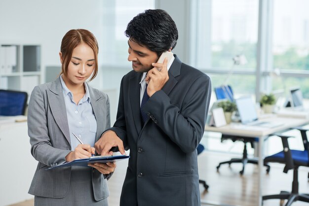 Man in suit talking on phone and woman making notes